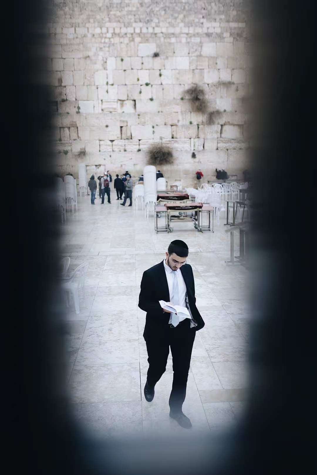 A person reading before a stone wall